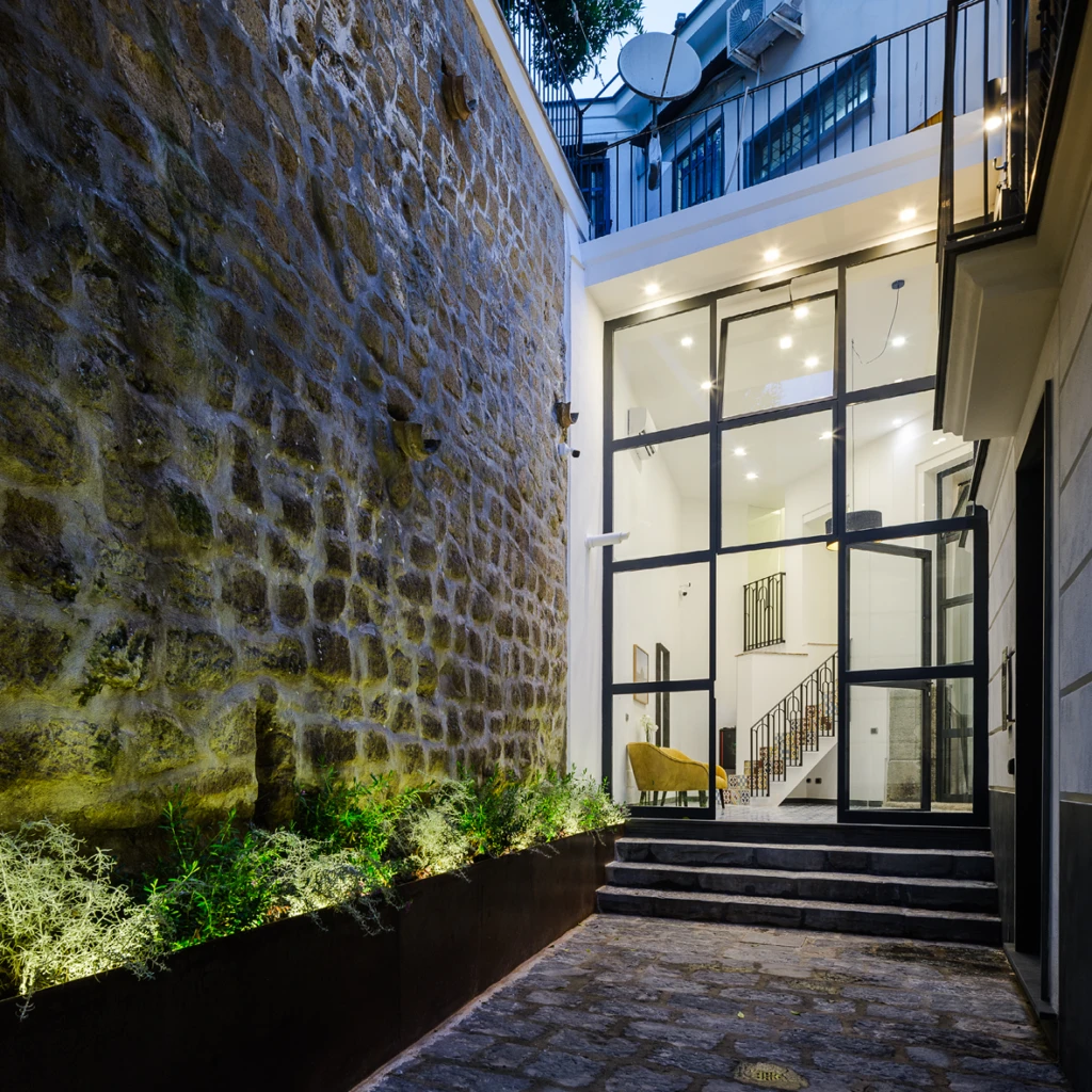 Ingresso notturno della residenza con muro in pietra illuminato